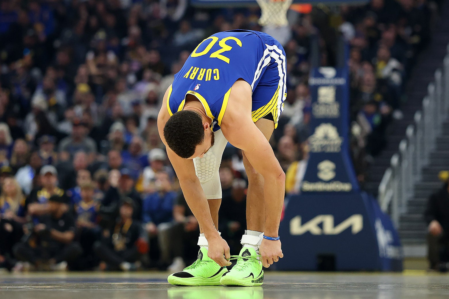 Steph Curry ties his shoes during a game. 