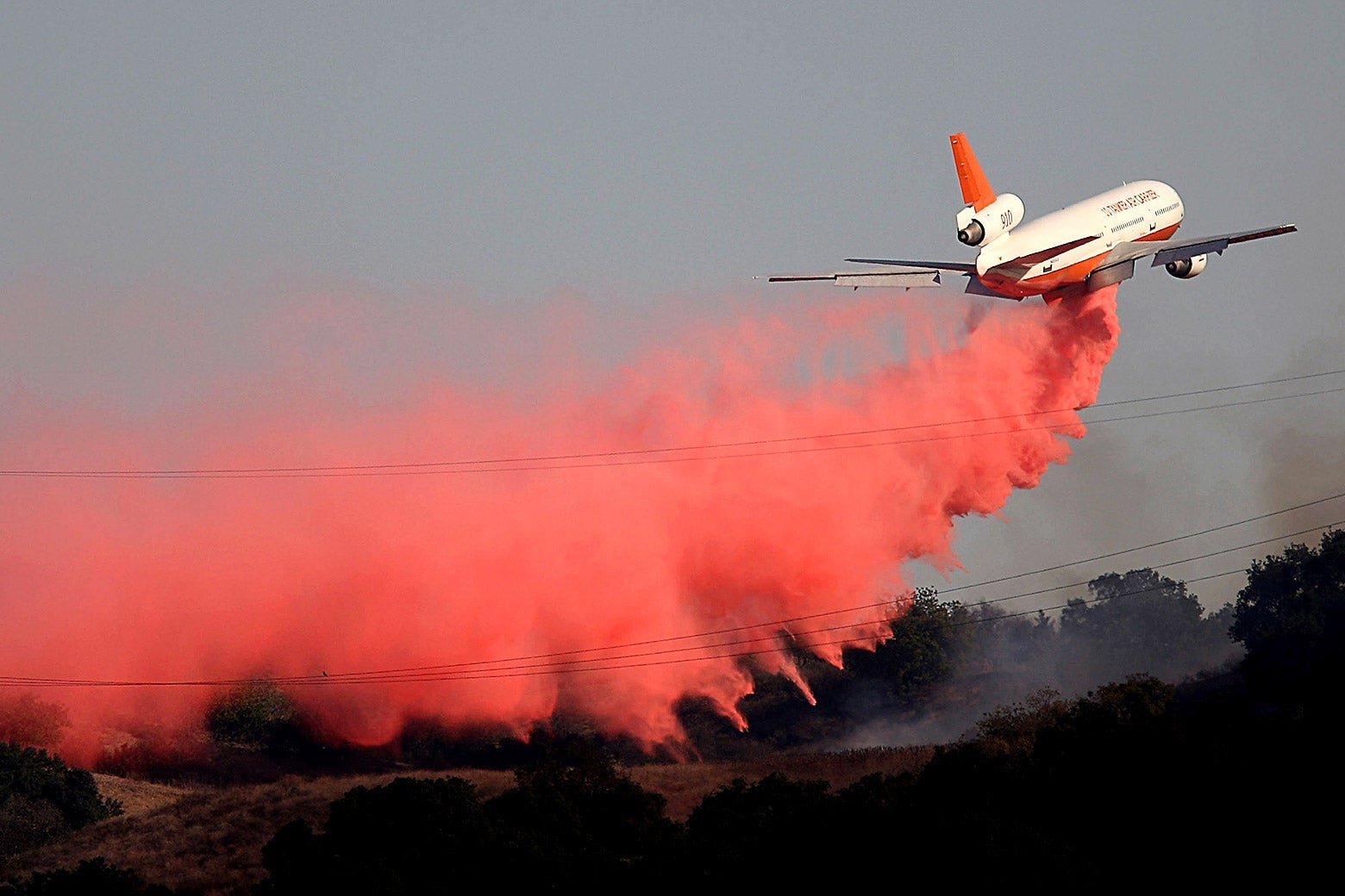 A plane leaves behind it a trail of red smoke.