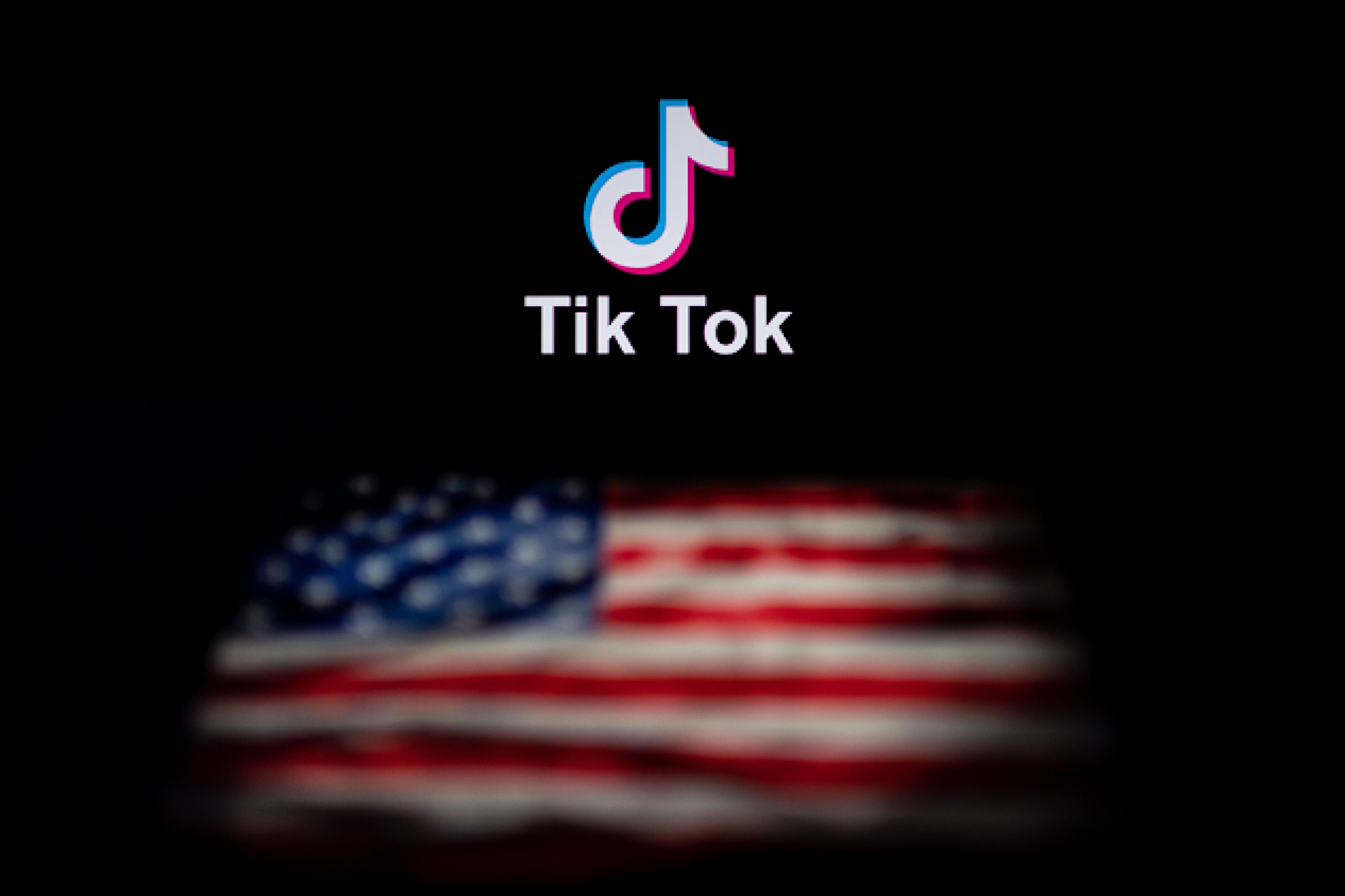 Two laptop screens with different images on them. The TikTok logo is on the first screen. The American flag is on the other. 