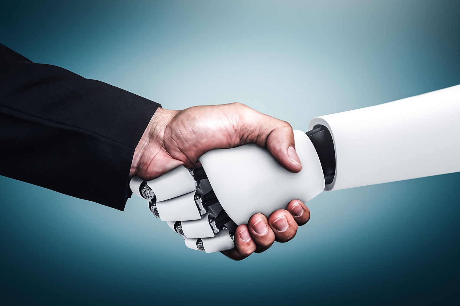 A robot hand and a human hand in a suit shake hands.