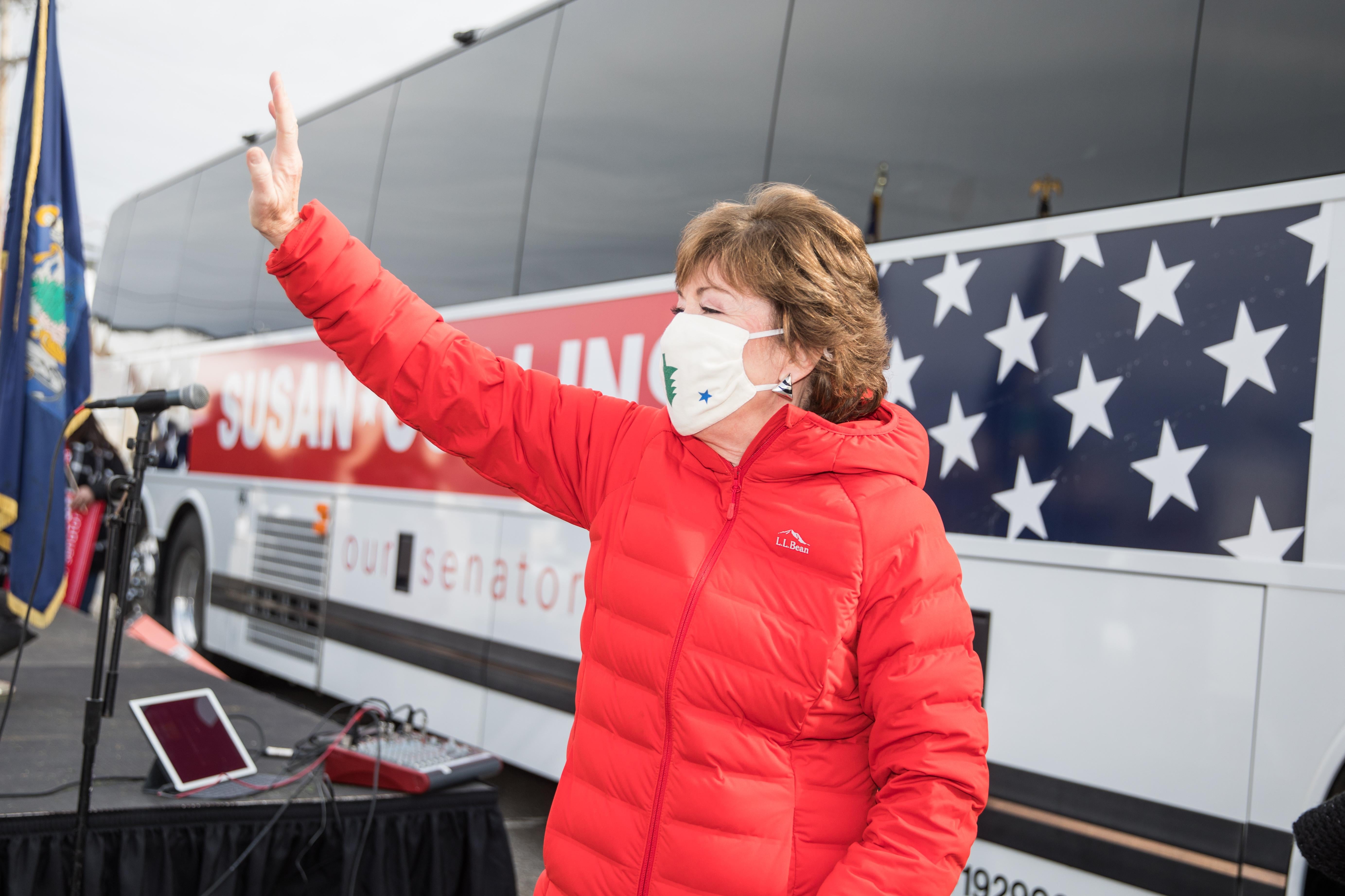 Susan Collins stands in front of her campaign bus, waving to supporters