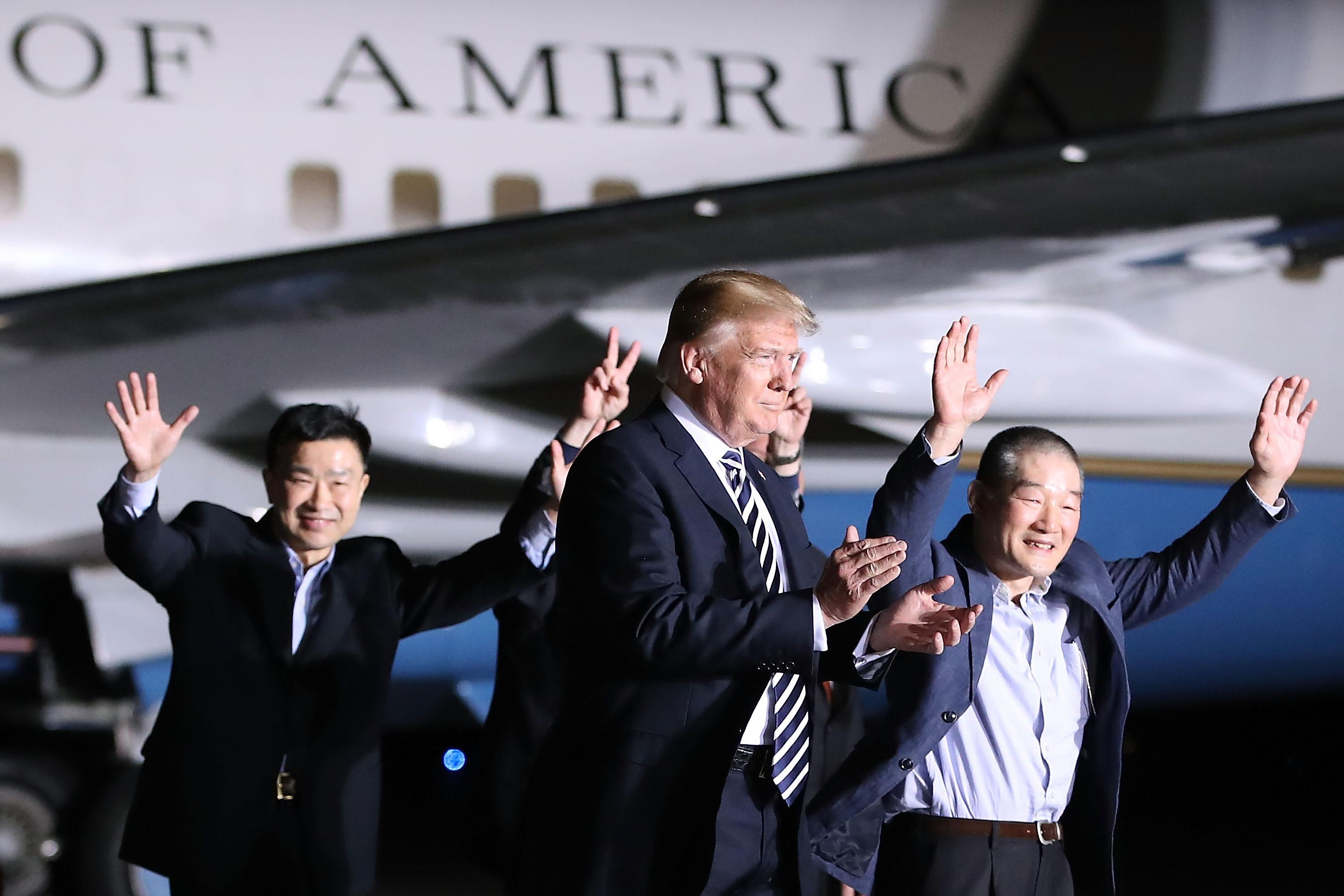 Trump walking beside Air Force One along with three dressed-up men waving.