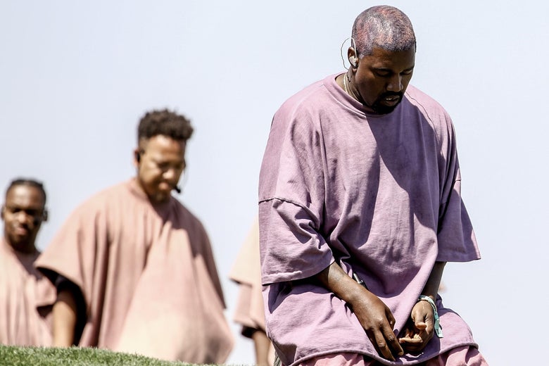 Kanye West, kneeling on an astroturf hill.