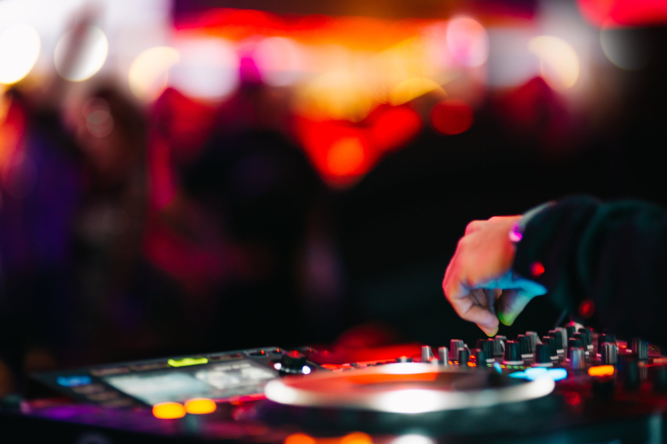 A DJ spinning in front of a dance club crowd.