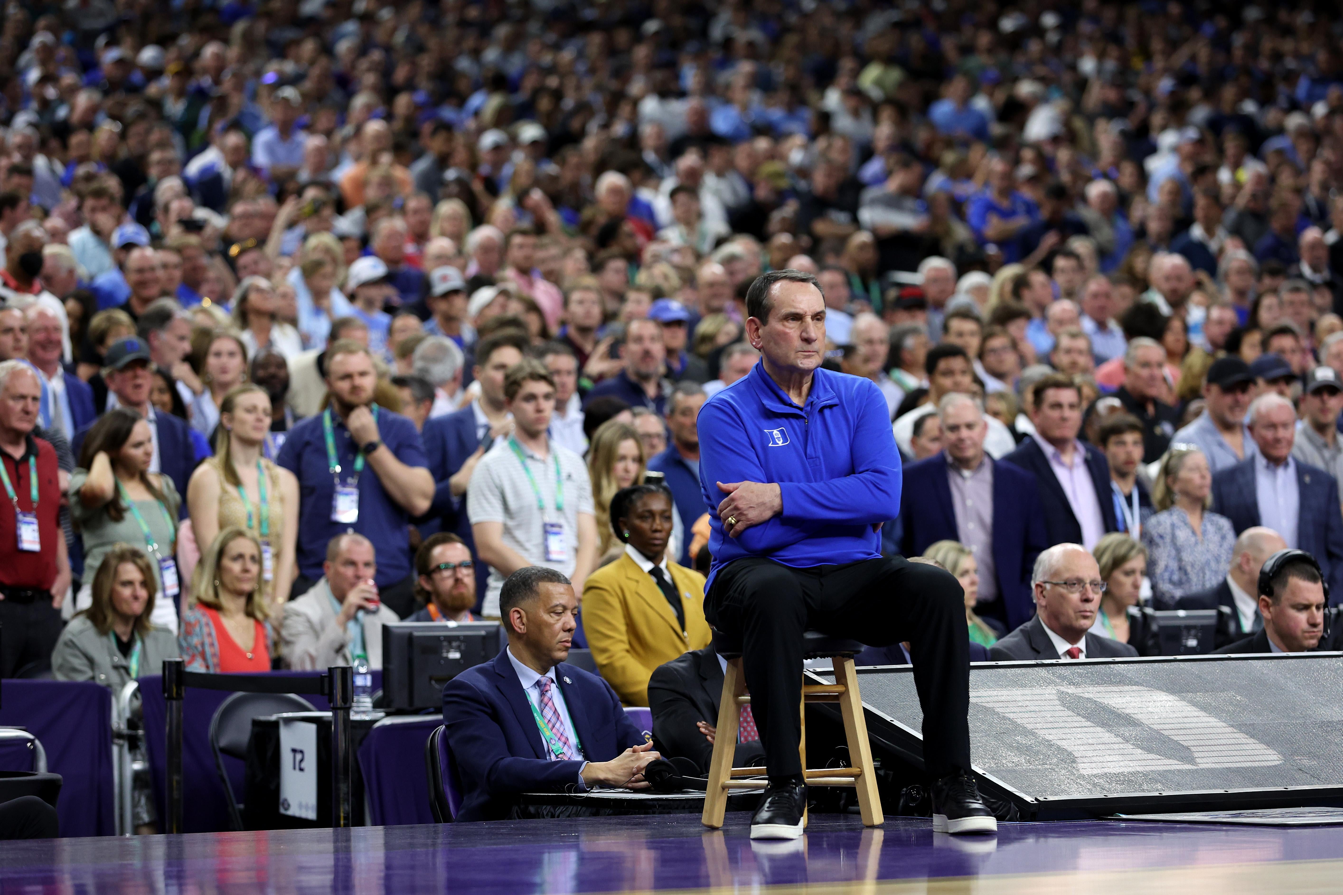 Head coach Mike Krzyzewski of the Duke Blue Devils sits in a chair on the sidelines.