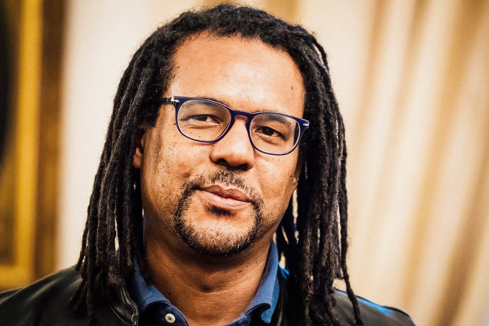 A Black man with dreadlocks and glasses.