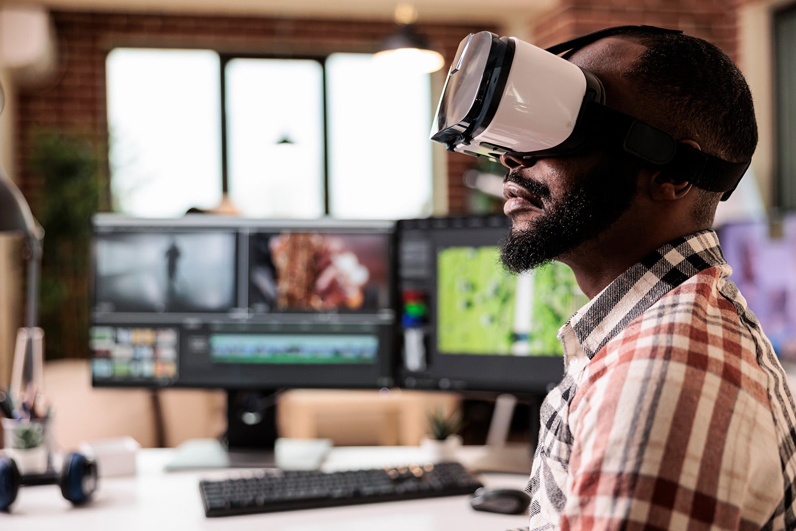 A man sits at a desk with a VR headset on.