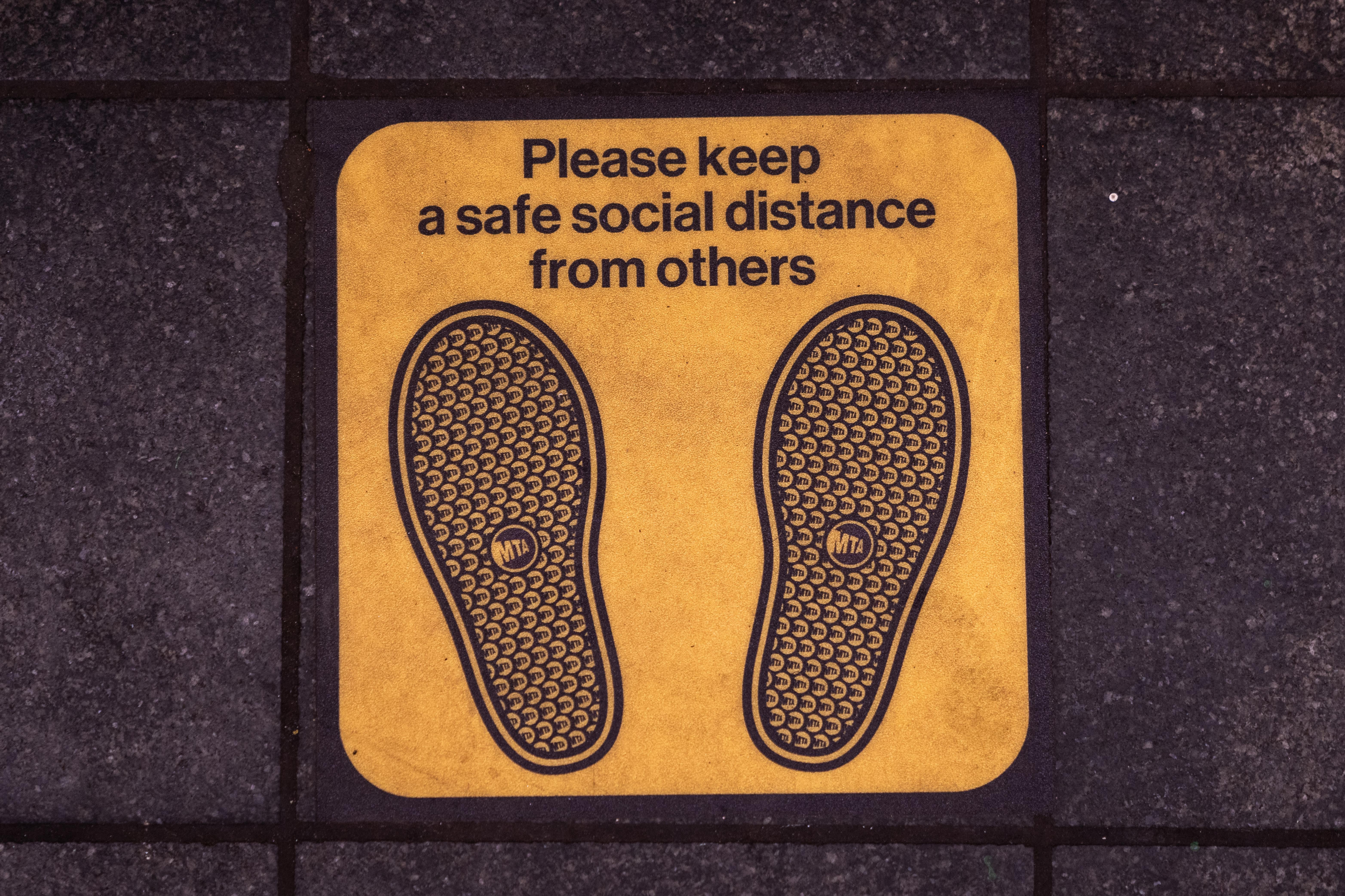 Signage on the floor of the Times Square subway platform asks commuter to maintain a safe social distance. 