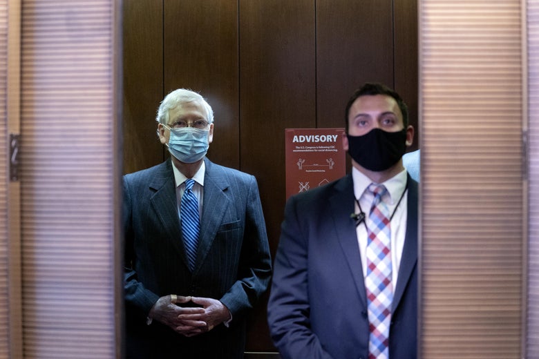 McConnell stands in an elevator with his hands clasped in front of him. His right hand is badly discolored.
