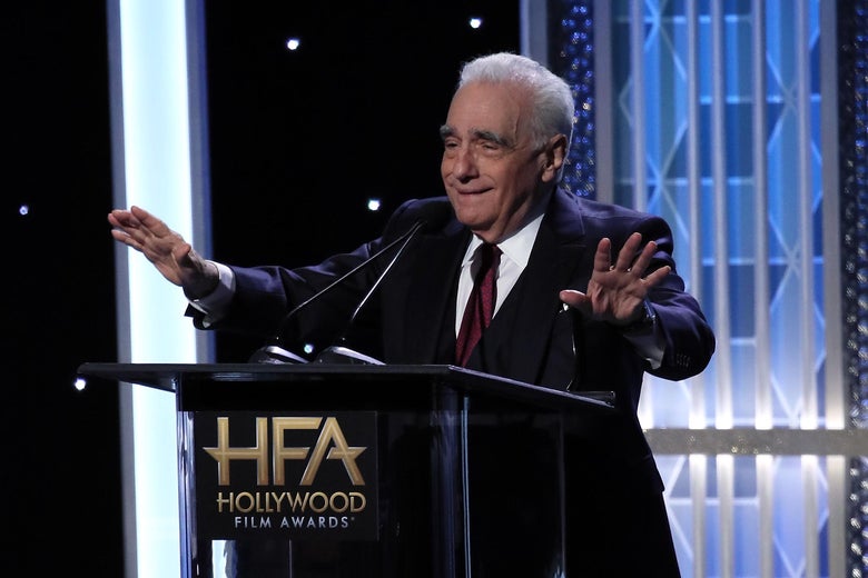 Martin Scorsese makes a "calm down" gesture behind a podium at an awards show.