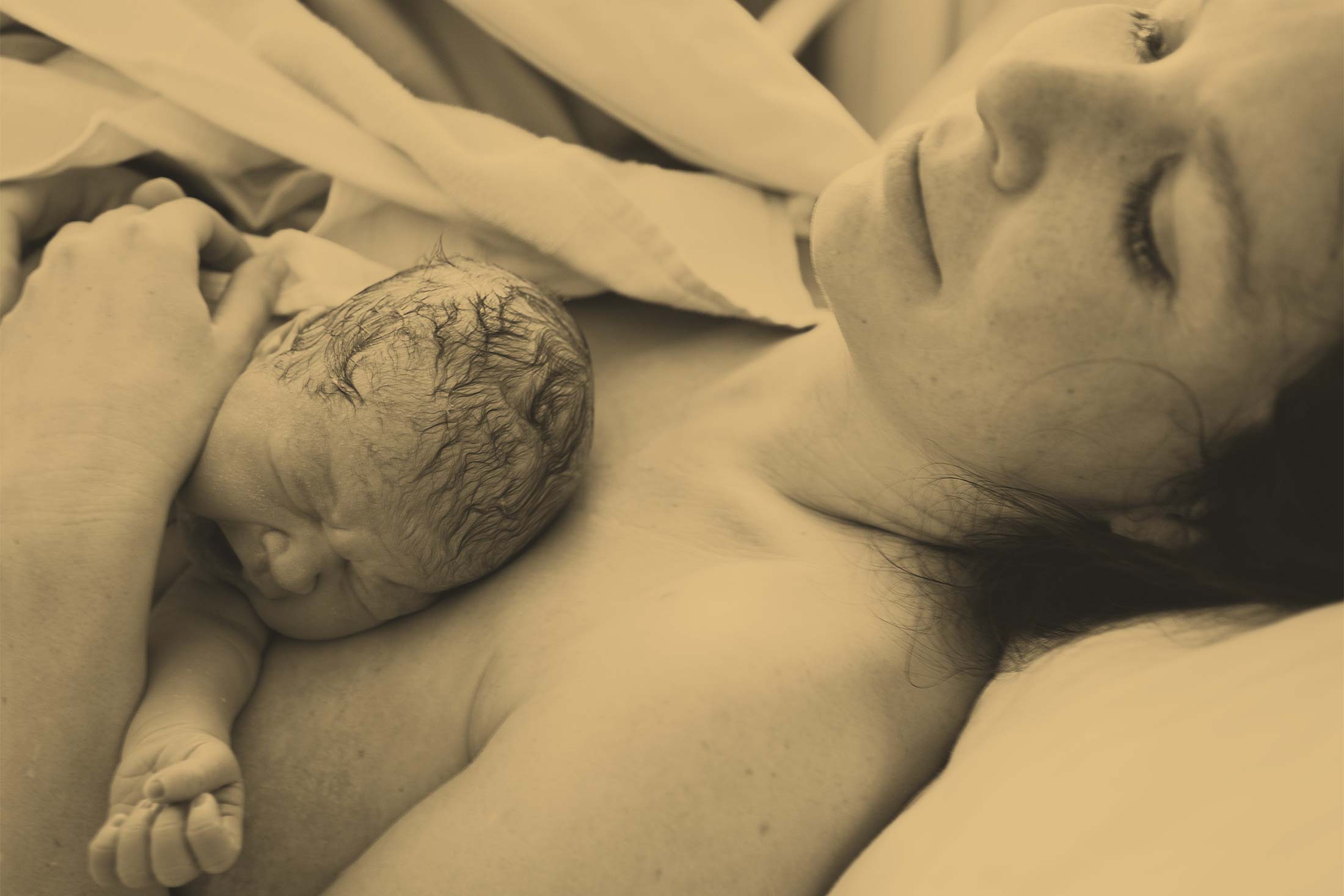A newborn lies on its mother's chest.