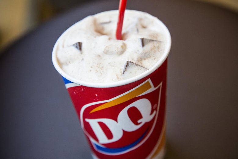 A S'mores flavored blizzard is seen at a Dairy Queen. It has a red straw, and the Dairy Queen logo.