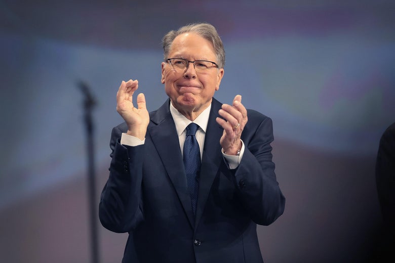 Wayne LaPierre applauds as he stands on stage.