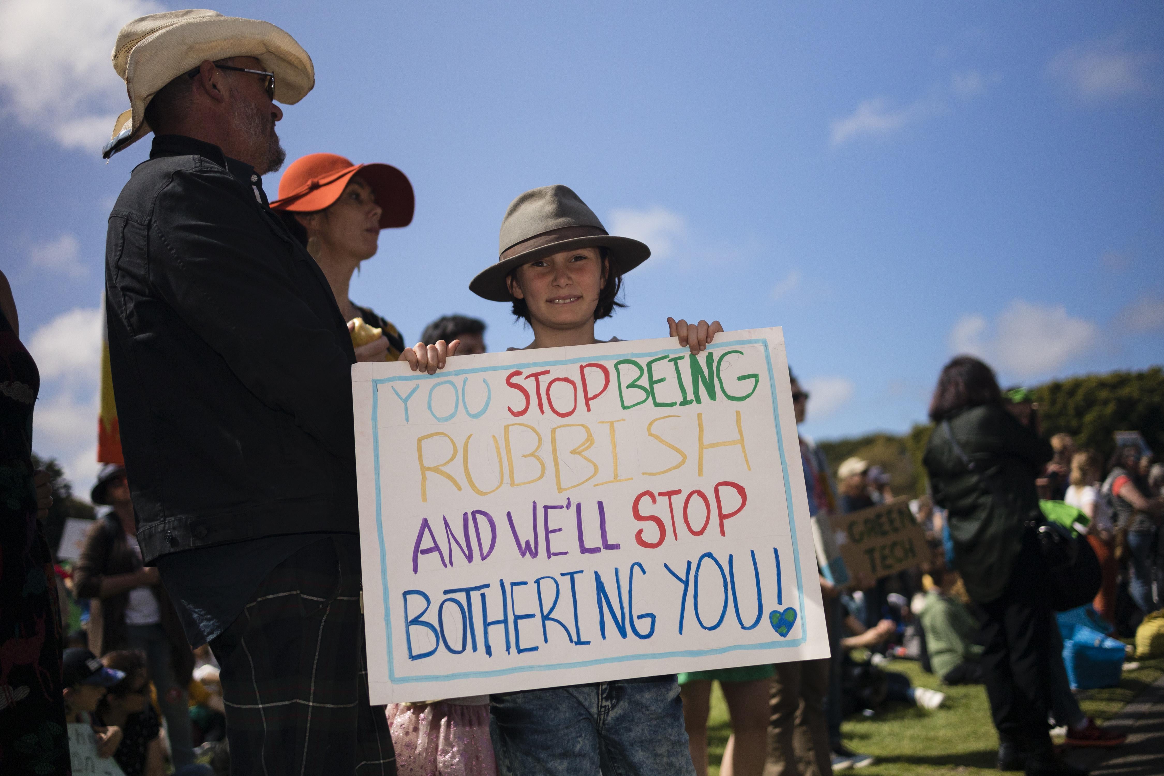 A young protester holds a sign that says "you stop being rubbish and we'll stop bothering you."