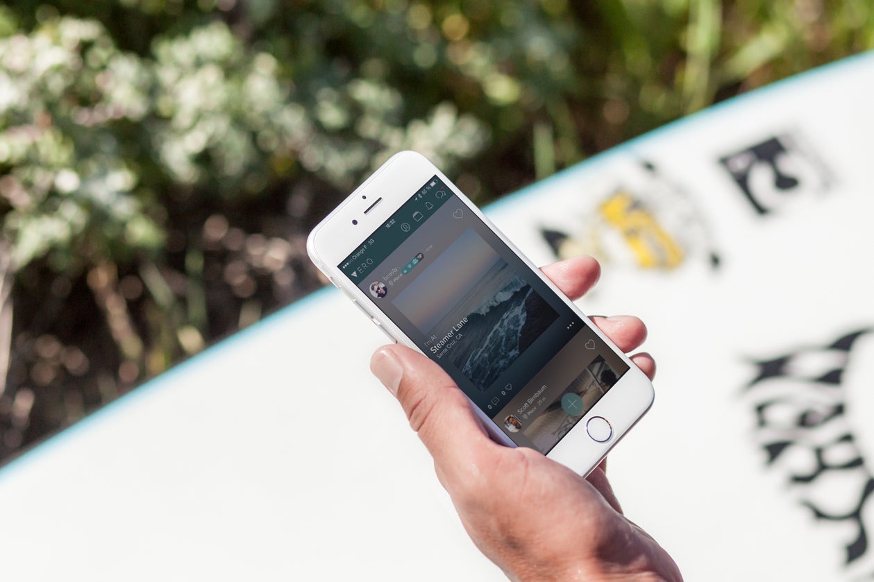 A hand holds a phone with the Vero app.