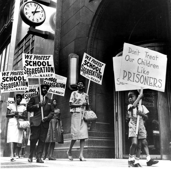 emonstrators, a young boy among them, picket in front of a schoo