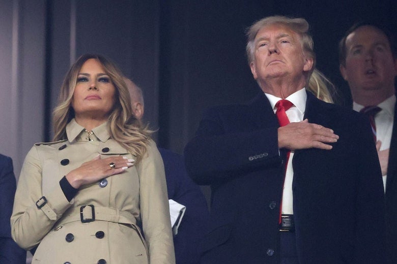 The Trumps, wearing coats, stand with their hands over their hearts.