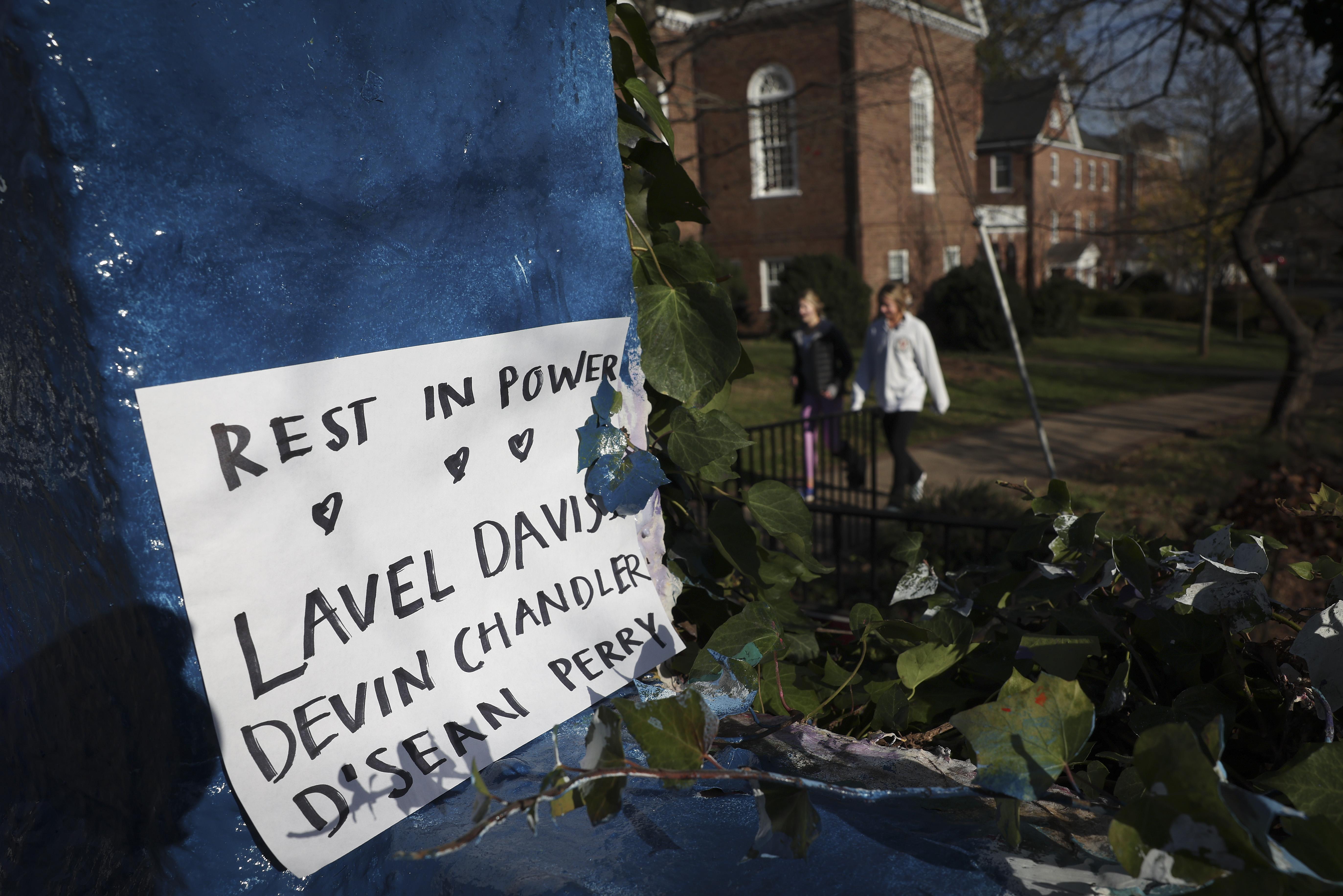 CHARLOTTESVILLE, VIRGINIA - NOVEMBER 14: Students walk past a sign memorializing three University of Virginia football players killed during an overnight shooting at the university on November 14, 2022 in Charlottesville, Virginia. The suspect, Christopher Jones, was apprehended this morning following the shooting where 3 people were killed and 2 others were wounded on the grounds of the University of Virginia yesterday evening. (Photo by Win McNamee/Getty Images)