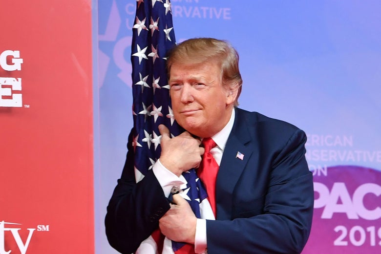 President Donald Trump hugs the U.S. flag as he arrives to speak at the annual Conservative Political Action Conference (CPAC) in National Harbor, Maryland, on March 2, 2019. 