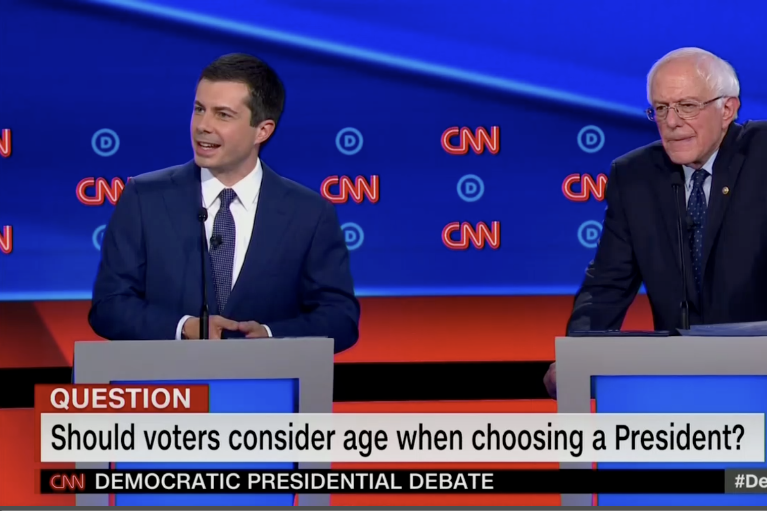 In this screengrab from CNN, Pete Buttigieg debates while Bernie Sanders makes a concentrating expression. The banner reads: "Should voters consider age when choosing a President?"
