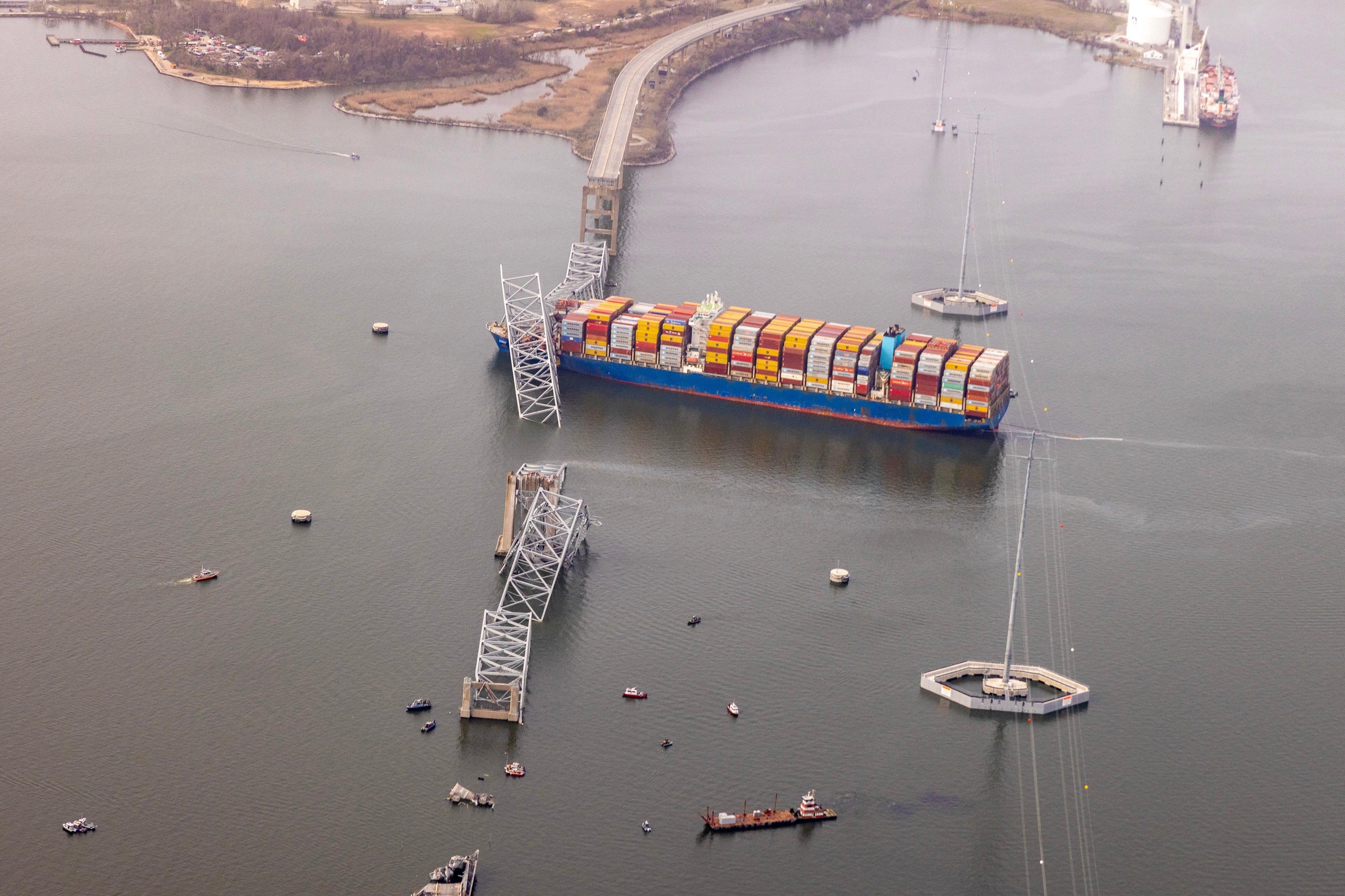 Aerial view of a cargo ship, with pieces of a bridge sticking out of the water.