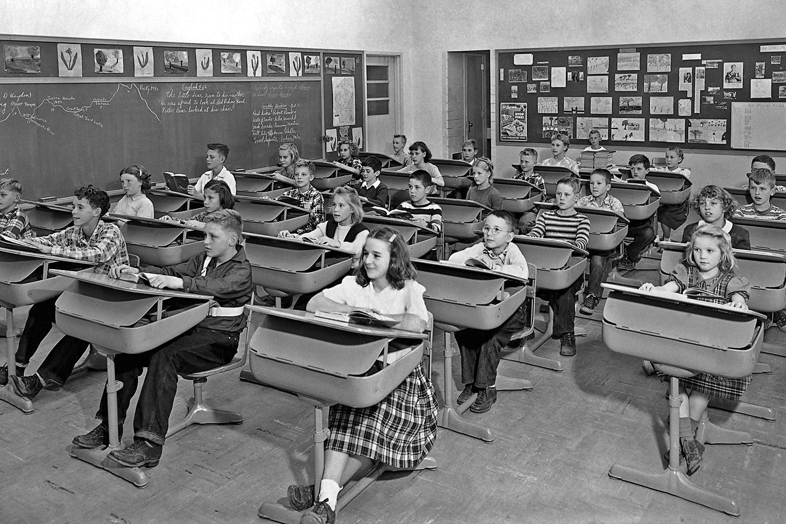 Children sit at desks in a classroom.