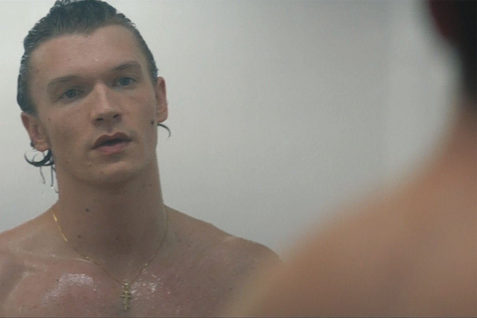 A man stares at another man in a communal shower.