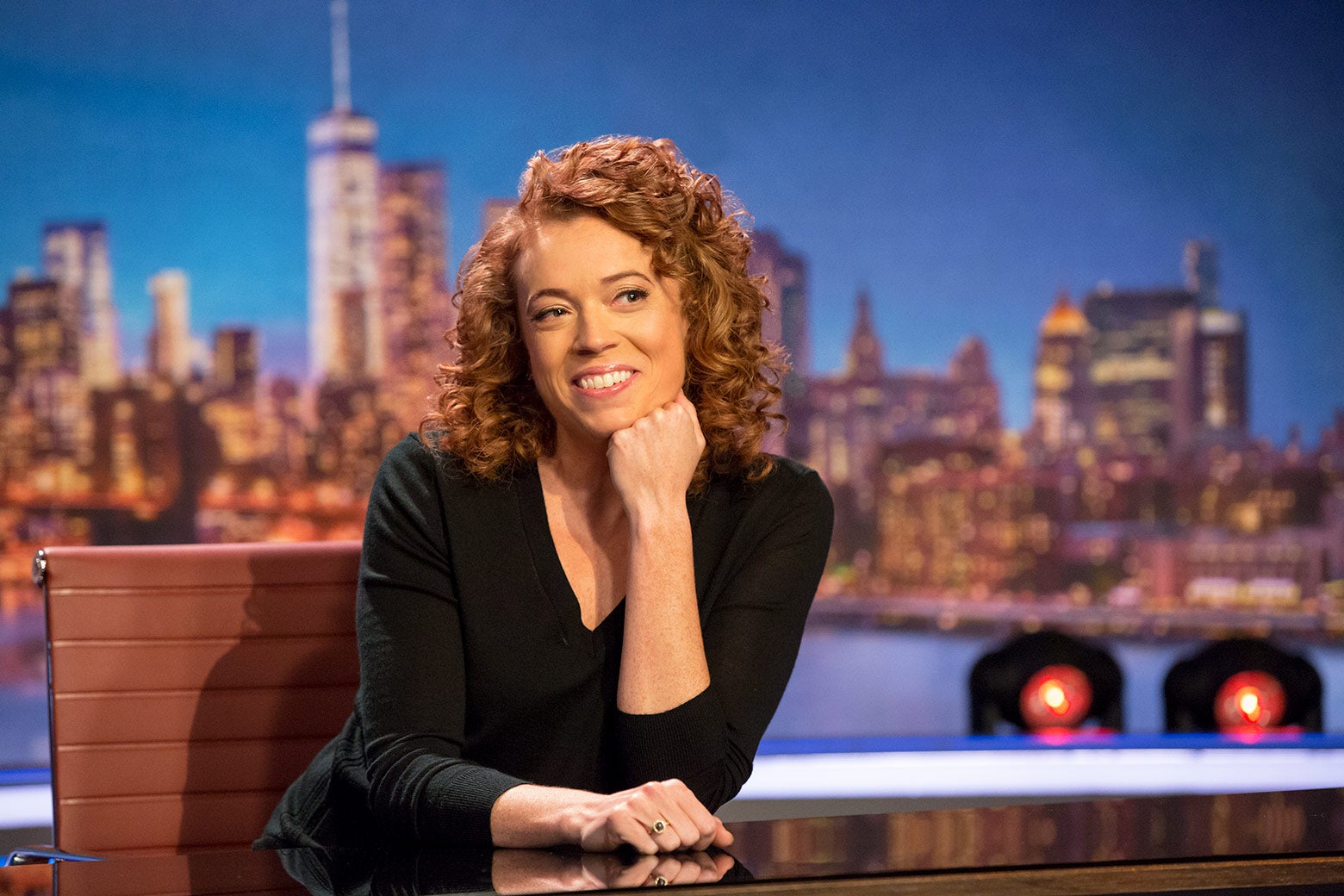 Michelle Wolf sitting behind a desk on the set of her show The Break.