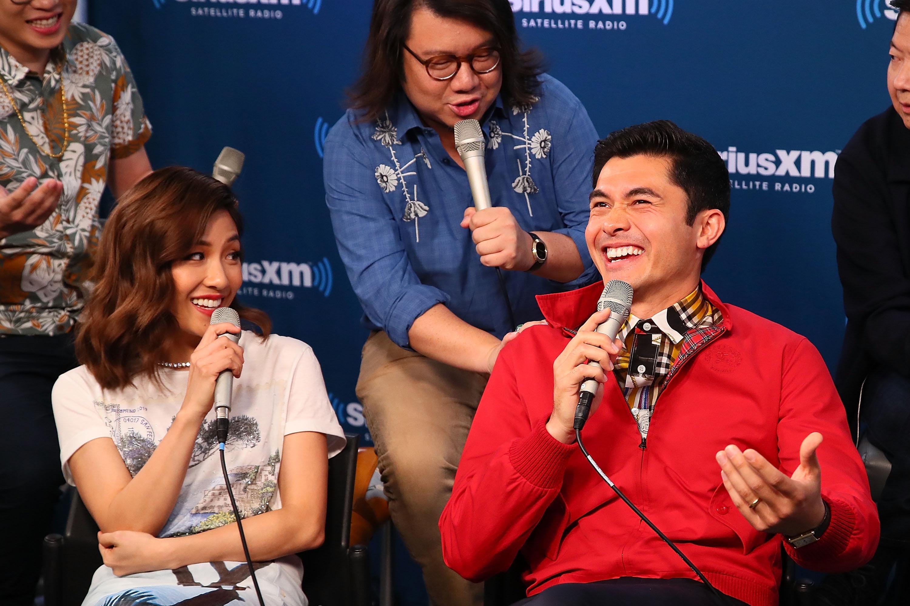The cast of Crazy Rich Asians talks into microphones for a radio show.