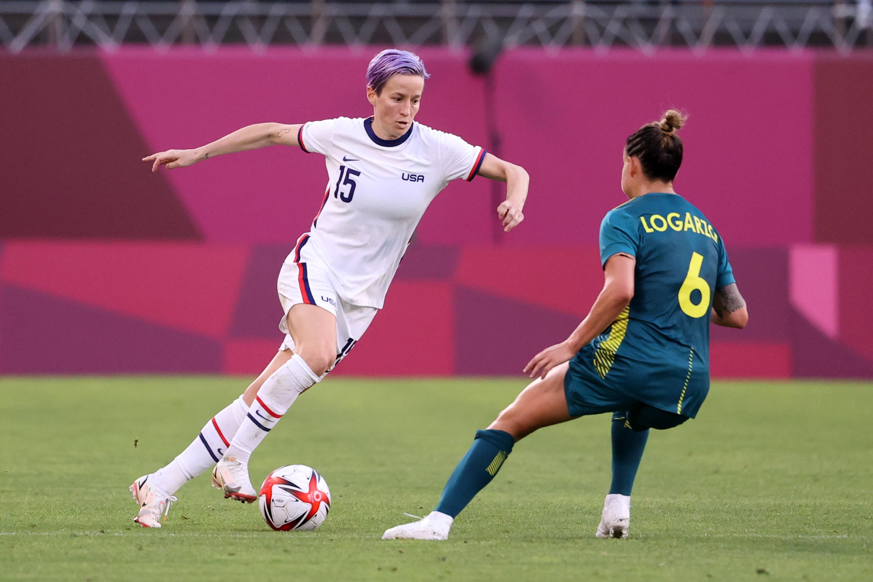Rapinoe lunging while dribbling the ball, with Logarzo defending tightly.