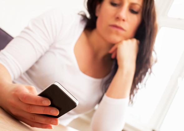 Woman looking at iPhone in disappointment