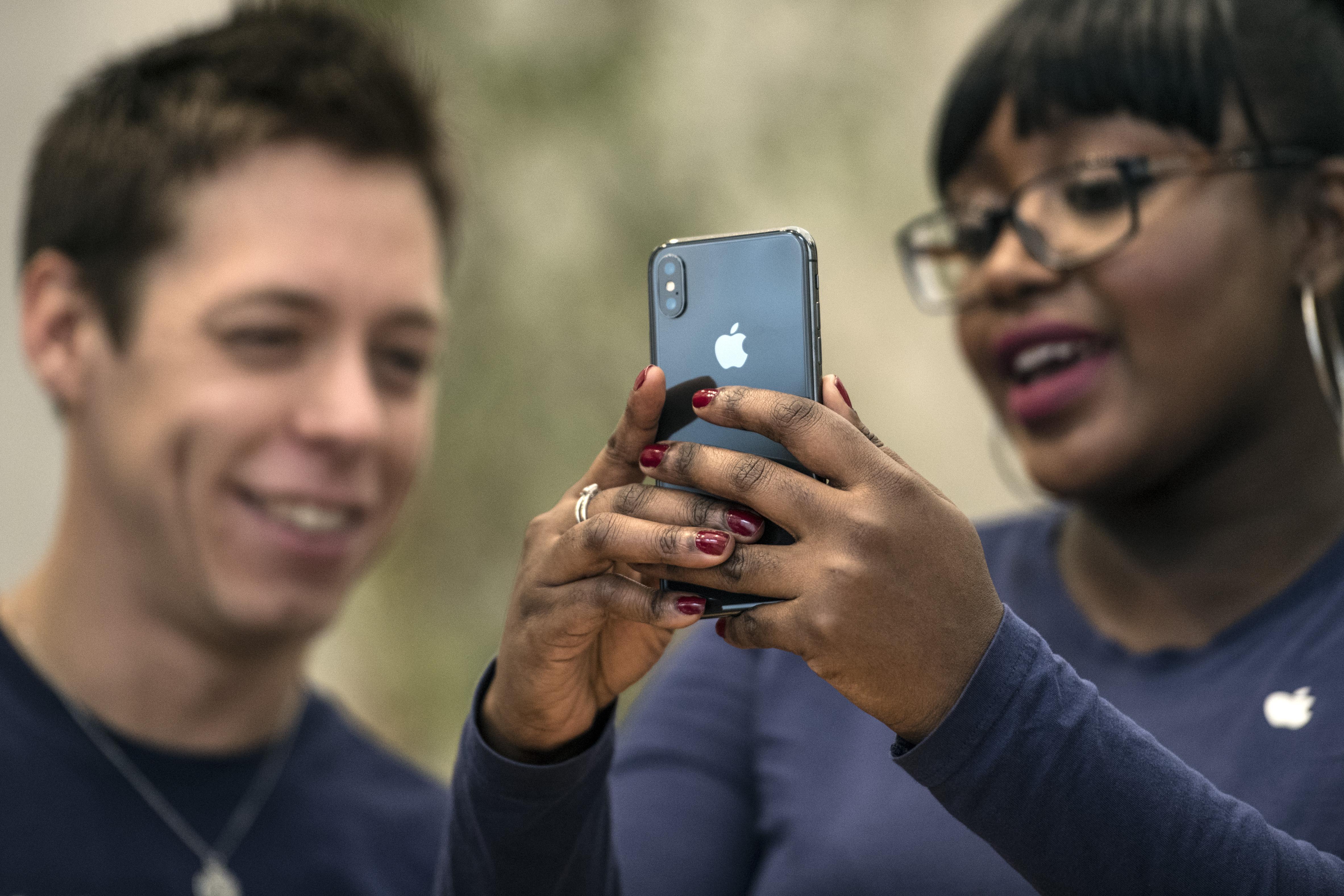 A staff member at an Apple Store in London unlocks an iPhone X with face recognition.
