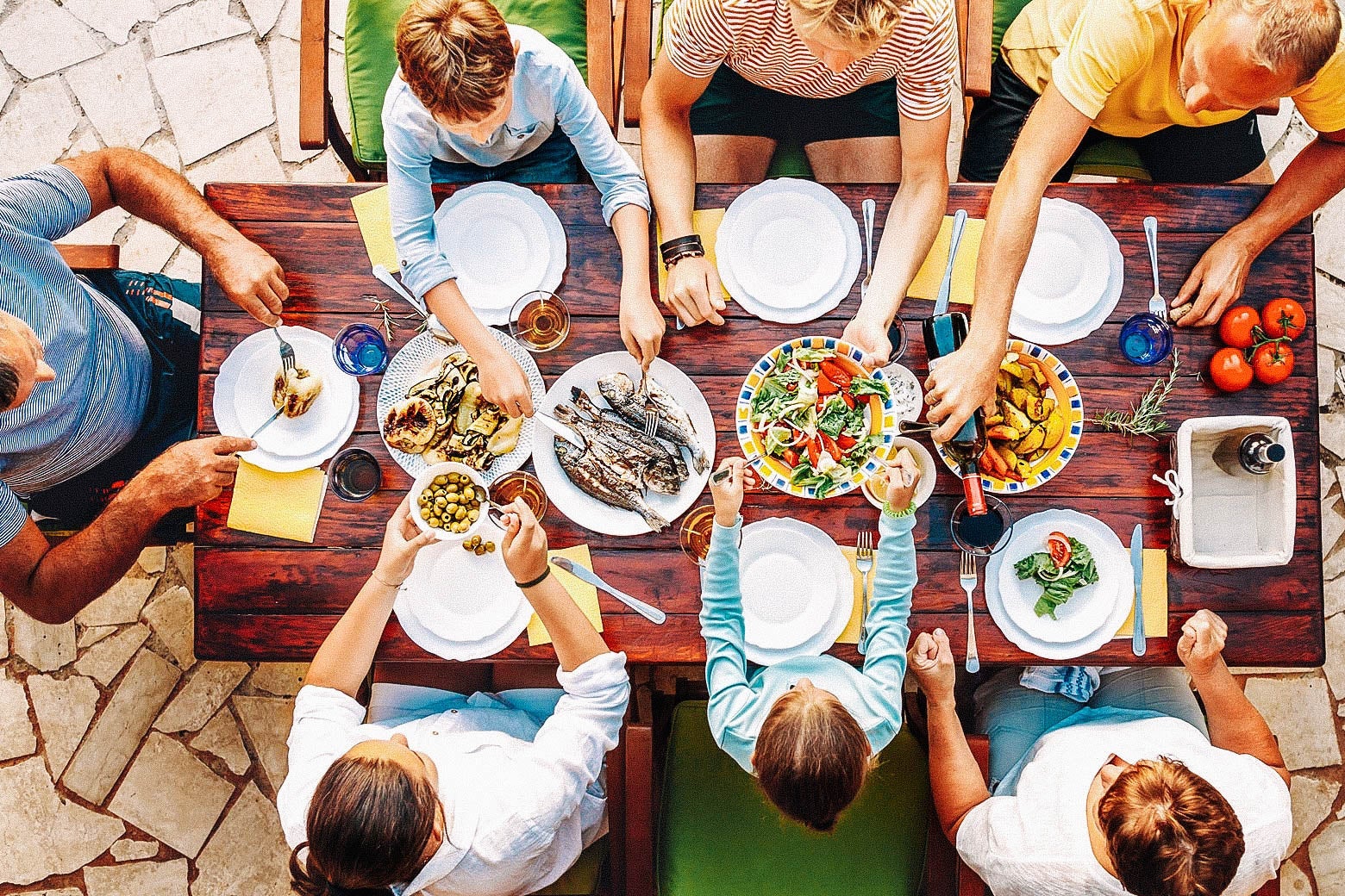 Overhead shot of a multigenerational family sharing a meal at a table outside on a patio
