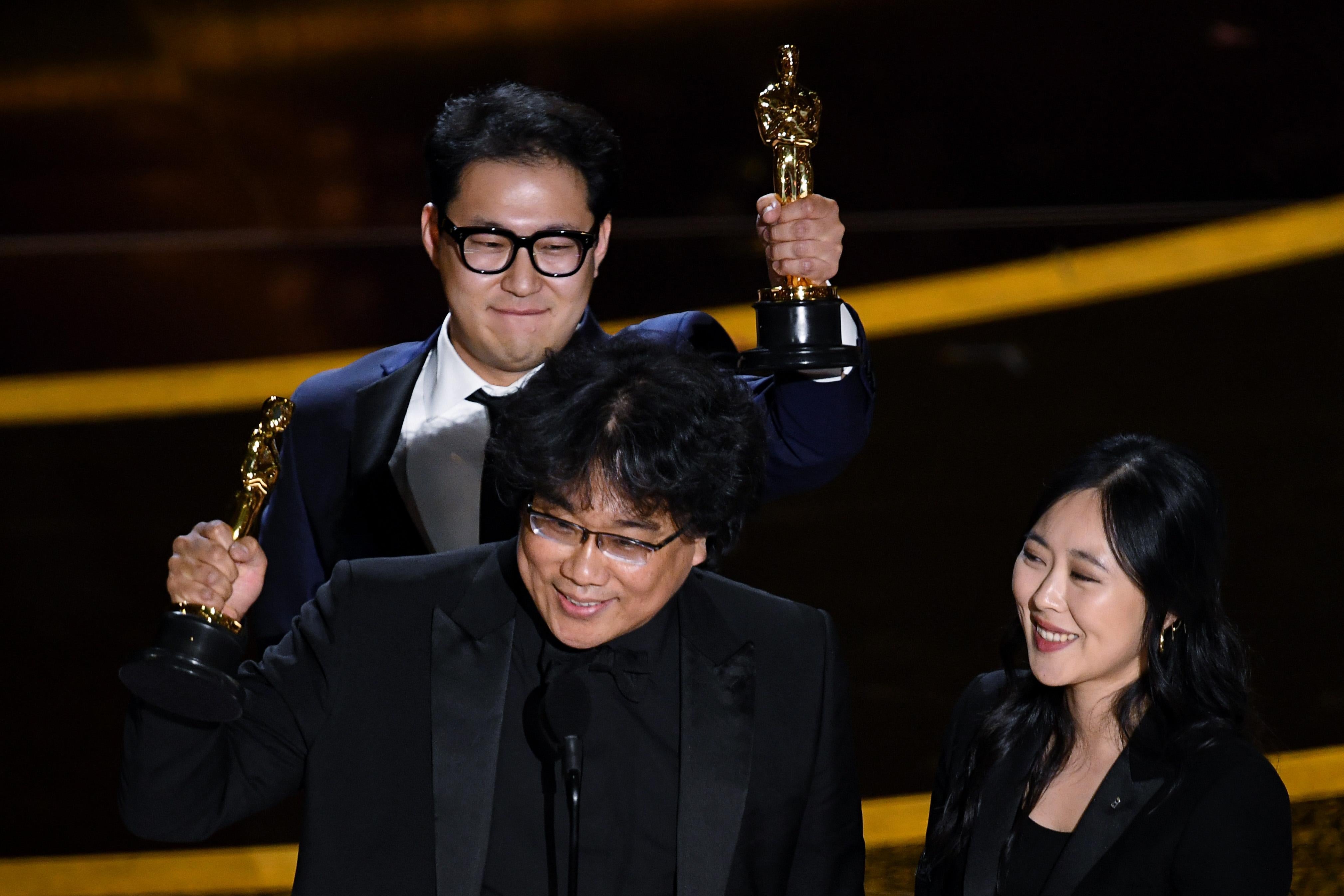 Bong and Han hold their statuettes aloft as Choi stands nearby.