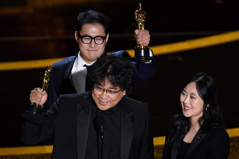 Bong and Han hold their statuettes aloft as Choi stands nearby.