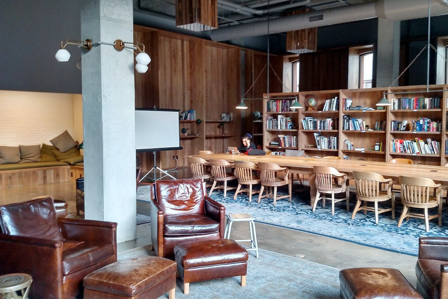 A tastefully decorated library with a long communal table and comfy chairs.