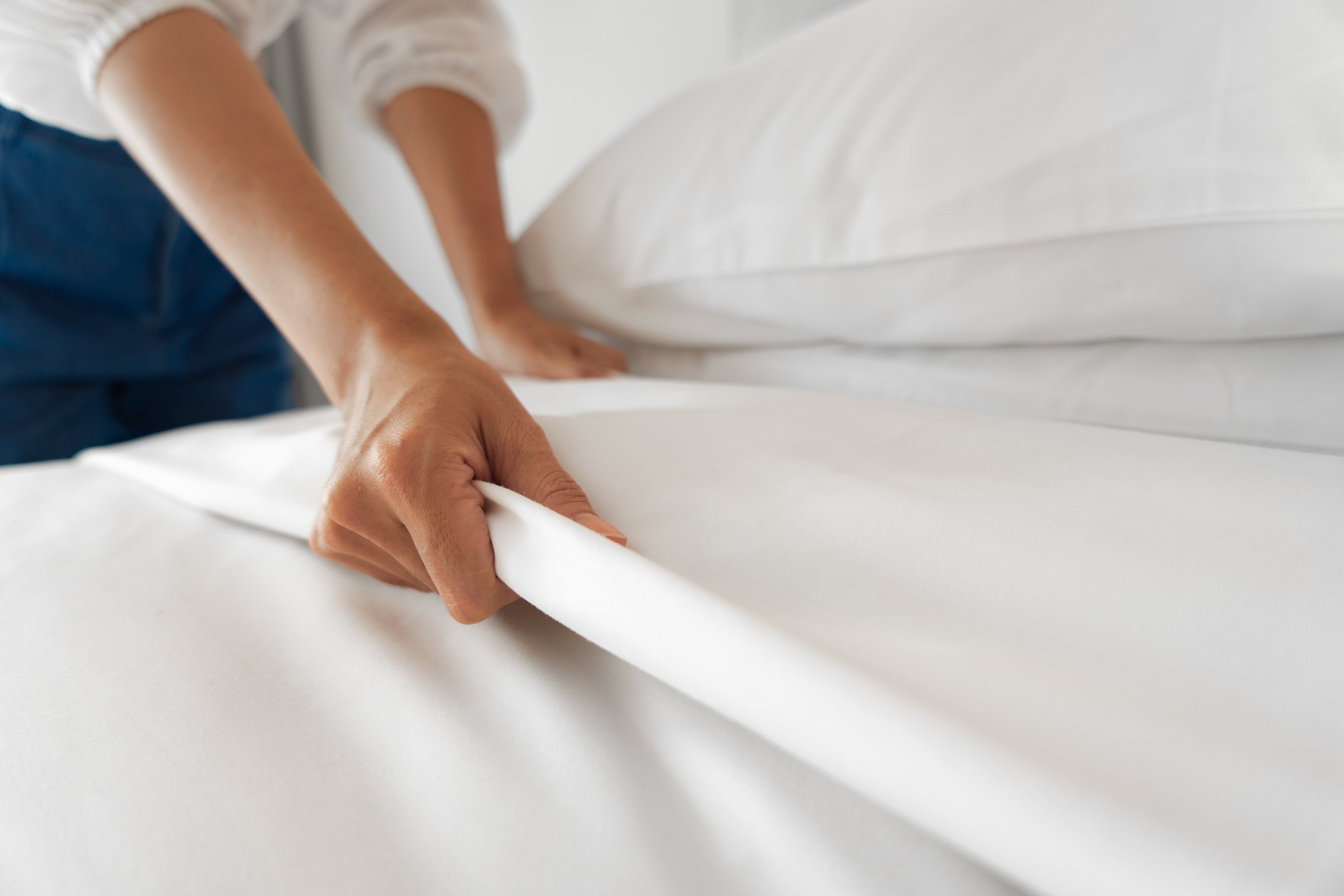 A pair of hands pulling on a sheet on a bed