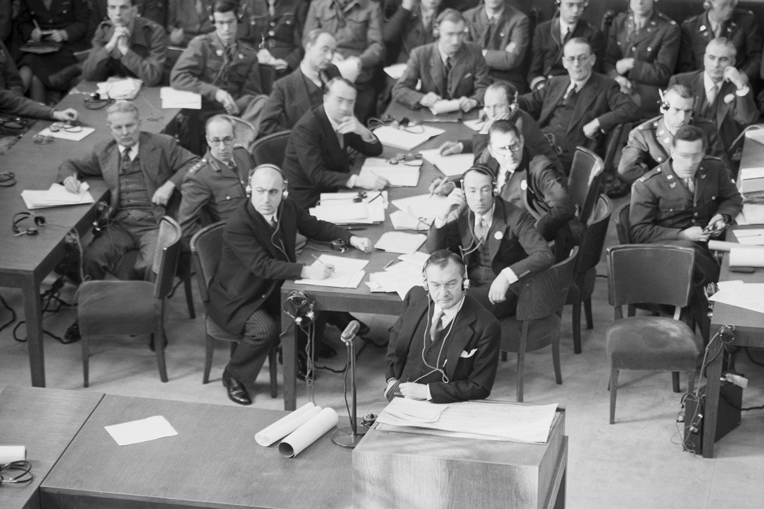 A black and white photograph of men in suits gathered for a hearing in Nuremberg, Germany, in 1945.