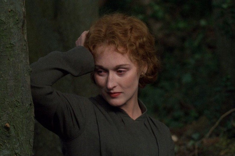 A young Meryl Streep leans against a tree in the woods while staring off into the distance.