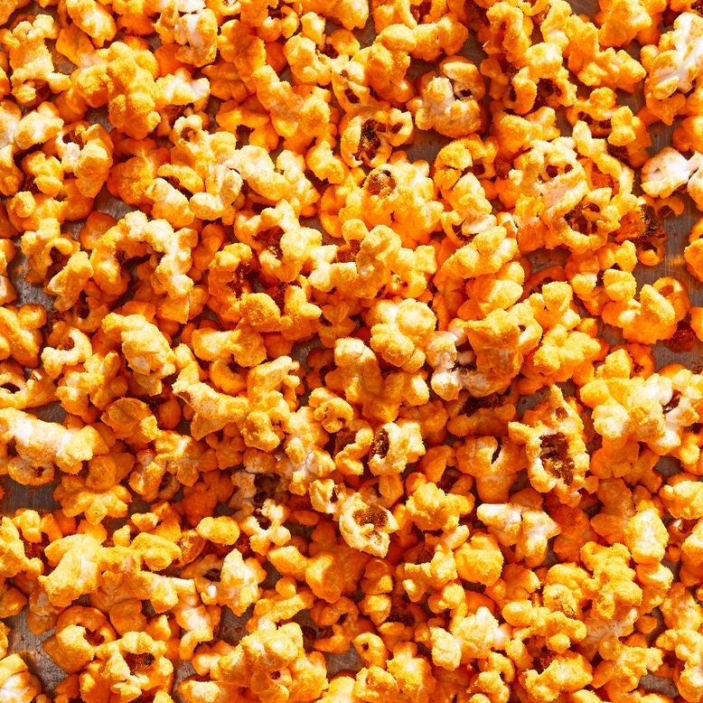 Popcorn covered in bright orange cheddar cheese powder