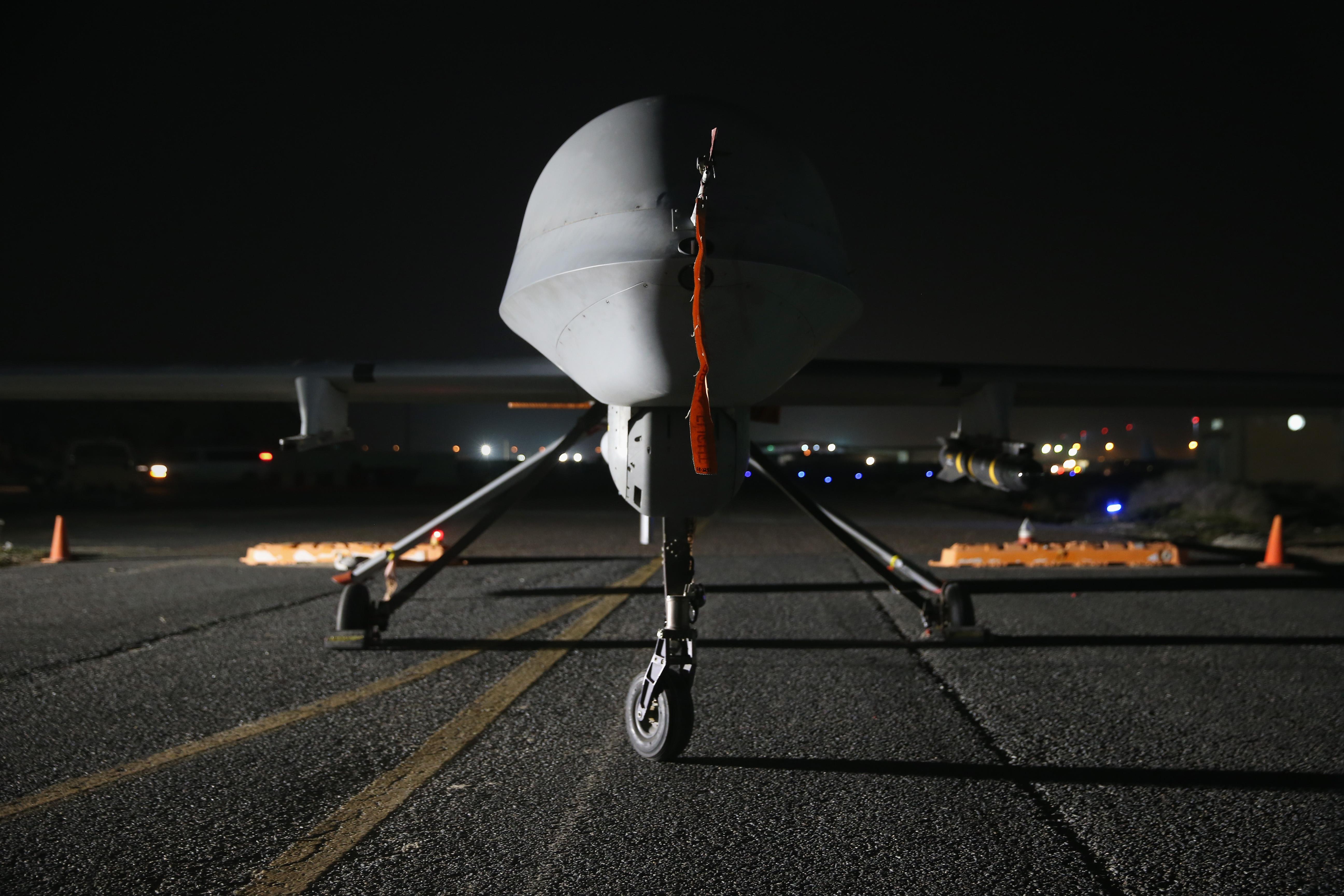 A predator drone on a runway at night.