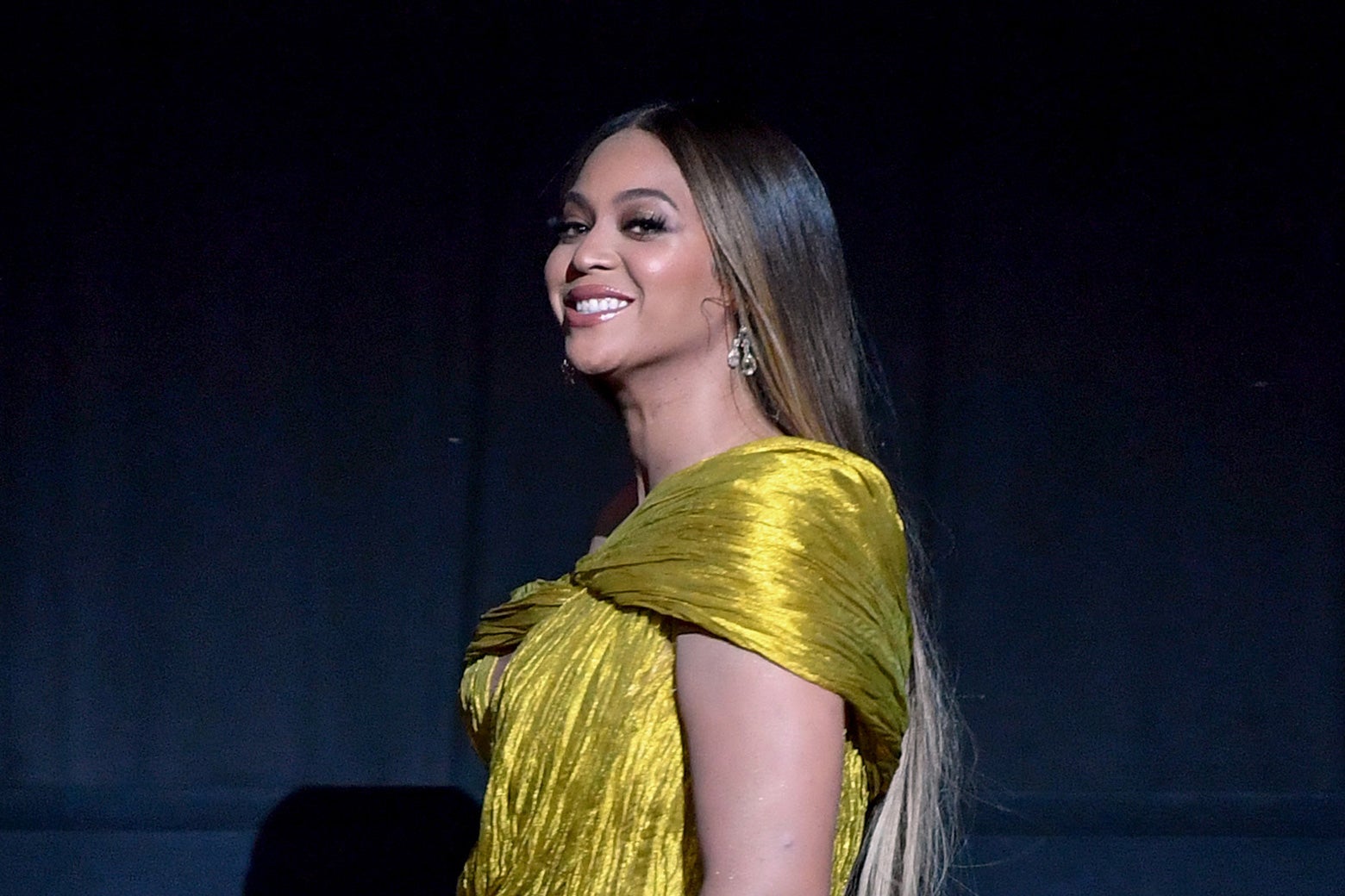 Beyoncé smiling in a gold dress.