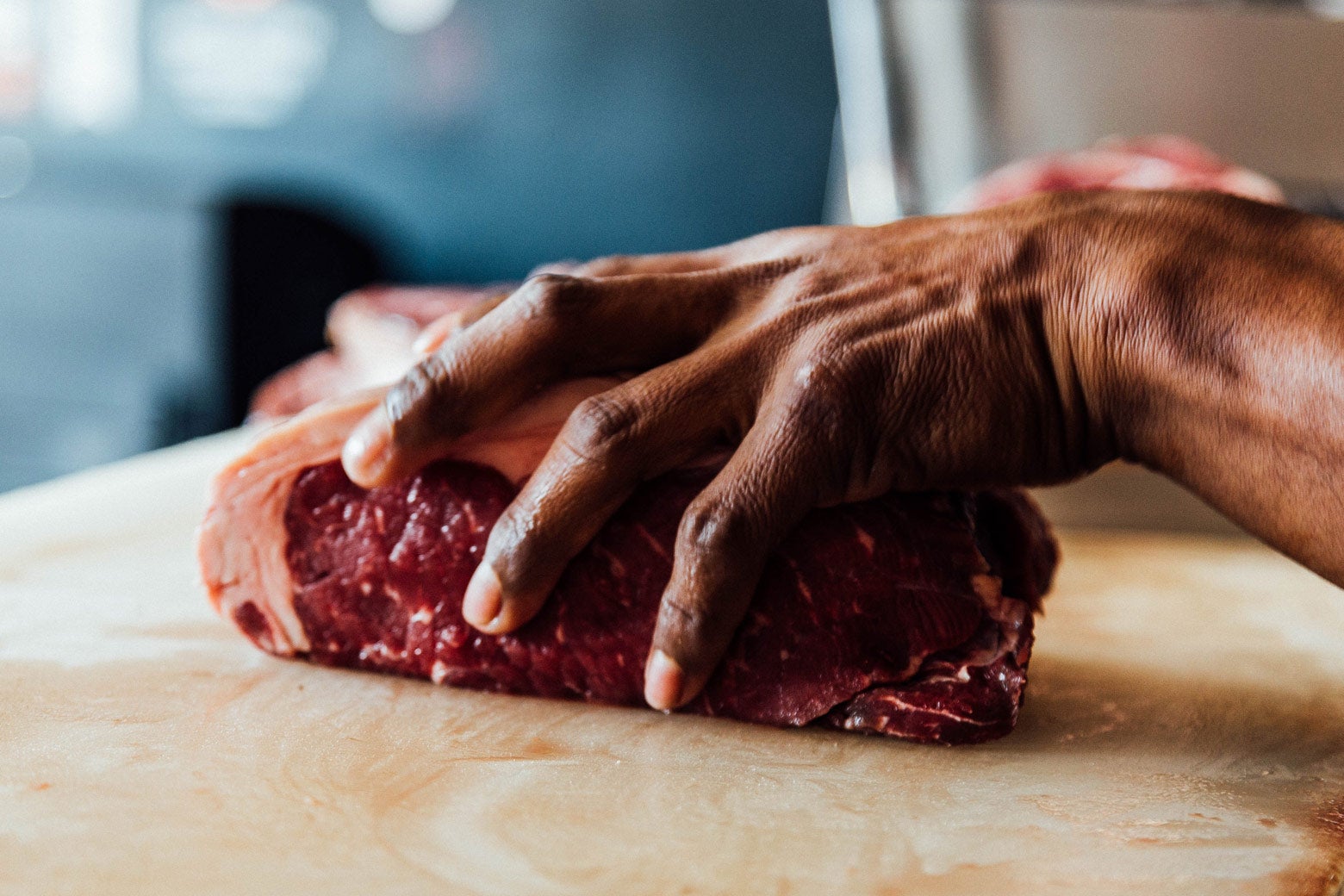 A hand over a slab of meat.