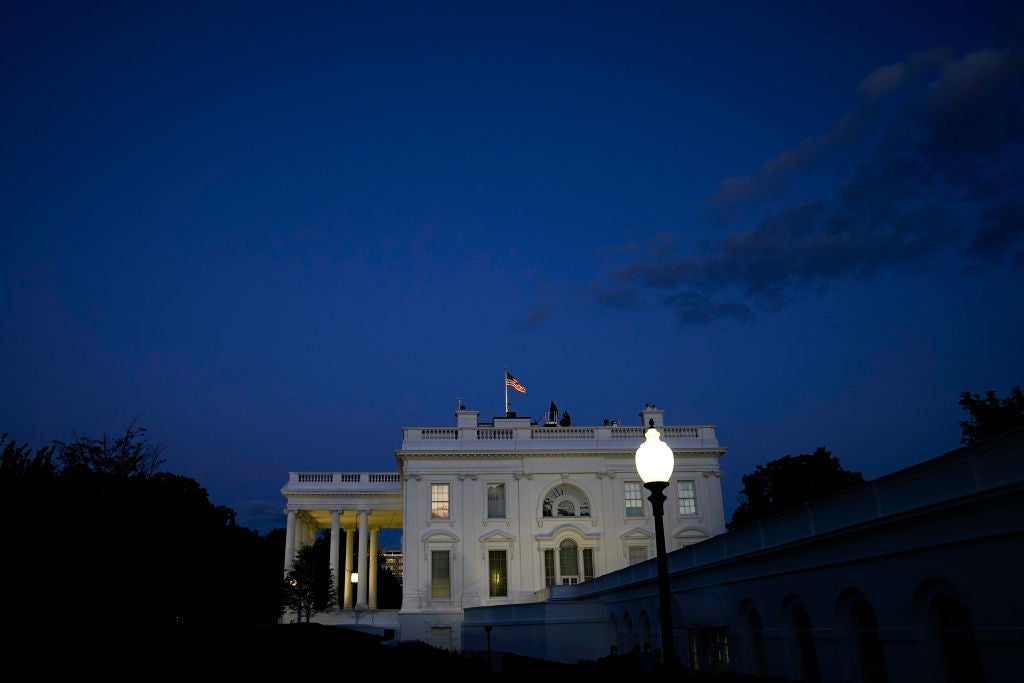 The White House is seen from the side against a darkening sky after sunset.