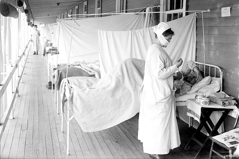 A nurse treating a patient in a sickbed, one in a row of beds stretching into the background, separated by curtains.