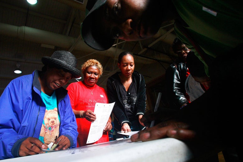 Black women stand in a line filling out ballots