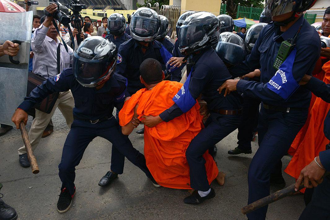 Cambodian security guards arrest an activist Buddhist monk during a protest in front of Phnom Penh municipal court on November 11, 2014. 