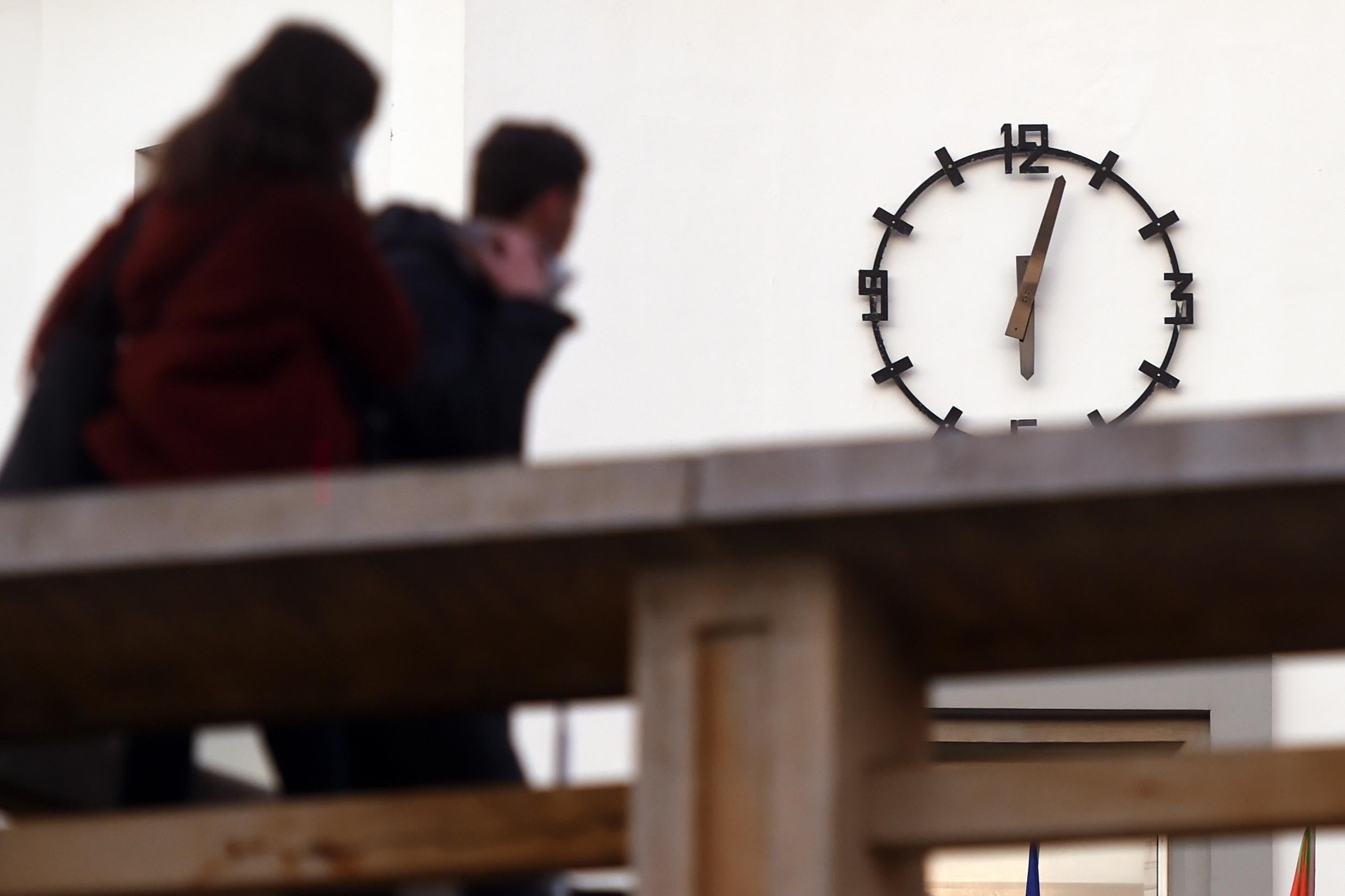 Two people look at a clock on a wall.