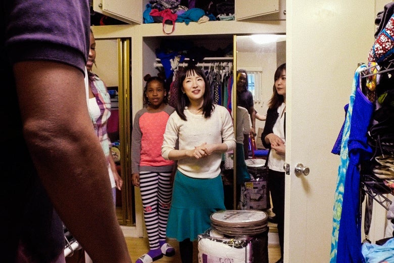 KayCi Mersier and Marie Kondo next to a closet, rack, and cabinet full of clothes.