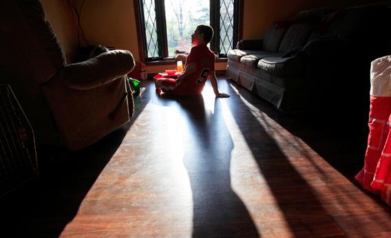 Parker Roos, who suffers from a form of autism called Fragile X, sits in the sun as he watches cartoons at his home in Canton, Ill., April 4, 2012.